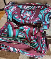 Two colorful patterned travel bags showing the style and wheels on larger bag