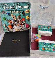 Game components including box, instruction sheet, wedge pieces, question cards, and black game folder.