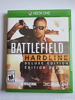 Photo of the front cover of the Xbox One Battlefield Hardline Deluxe Edition video game case showing cover art and ratings.