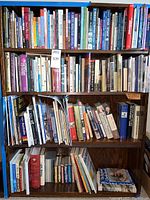 Full bookshelf showing a wide range of printed books including history, fiction, nonfiction, and Alaska-related books.