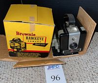 Brownie Hawkeye camera flash model in its original yellow and black box, showing front and side of box and flash model.