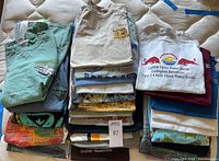 Overview of stacked assorted t-shirts showing different prints and colors