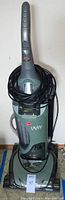 Front view of Hoover Savvy upright vacuum cleaner with wrapped black power cord and clear dust bin.