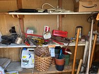 Shelves filled with assorted hand tools including oil cans, broom, wrenches, planter baskets, chemical container, and various small tools.