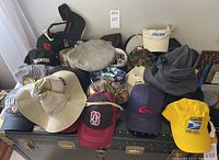 Wide shot showing many baseball-style caps in colors including black, navy, and camouflage. Includes sun hats and visors visible on top and the front.