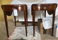 Pair of vintage drop leaf end tables showing overall front and side profile with drawers and drop leafs in up position.