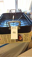 New turkey roaster pan in box with metal rack and handles.