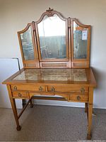 Full front view of vintage wooden dressing table with tri-fold adjustable mirror and four drawers.