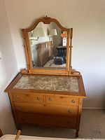 Front view of dresser showing four drawers and swivel mirror on top. Glass inset top with floral fabric underneath visible.