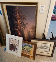 Full view of all six pieces including large framed sequoia tree, smaller framed paintings and drawings, and iron wall art with moose antlers.