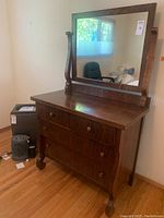Full view of antique dark wood dresser with attached large rectangular mirror in a simple straight line design.