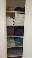 Shelves filled with stacked bath towels and rugs in multiple colors
