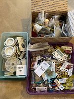 Three plastic containers filled with loose bead strands, spools of wire and hardware