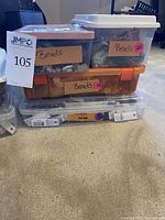 Four clear and orange plastic storage boxes stacked on floor, labeled 'Beads'