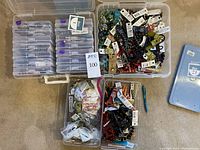 Overhead shot of four plastic storage boxes containing mixed bead strands and loose beads with tags
