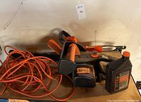Photo showing Remington chainsaw with lubricant and orange extension cord on table