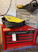 Red Craftsman multi-drawer tool storage with contents, drills and hardware organizer on top.