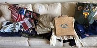 Overview of uniforms, helmet liner board, flags and accessories on couch