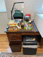 Office supplies on a desk: scrap bin, shrink shredder, clip-on light, file folders, scissors, stapler, legal pads, and organizers