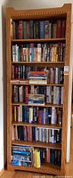 Front view of the tall oak bookcase filled with books