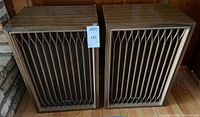 Photo showing both vintage Kenwood speakers side by side on floor, wood cabinet and vertical wavy grille design visible.