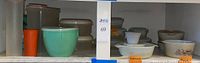 Wide shot of shelf holding multiple vintage kitchen containers including Pyrex, Tupperware, and glass storage.