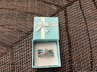 Ring in light blue gift box, viewed from top, showing blue pearl and clear stones on white gold band