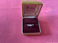Ring displayed in a small velvet‐lined presentation box with “Tradition” label