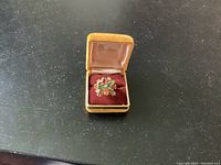 Ring inside an open jewelry box showing front face with four stones in a high gold plated setting.