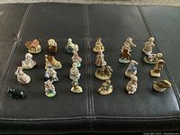 Entire set of 24 Wade ceramic nursery rhyme figurines displayed on black surface, showing various small colorful characters including animals, children, and objects.