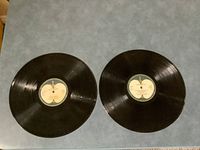 Two black vinyl records showing cream colored Apple labels on center