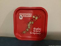 Photo of red square metal tray with Shepherd Neame branding and hop design.