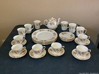 Photo showing the entire set including six dinner plates, six B&B plates, six cups, six saucers, six mugs, and a teapot arranged on a table.