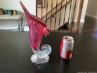 Side view of cranberry tulip-shaped glass vase placed next to a soda can for size reference showing the elongated shape and swirl base.