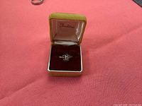 Gold ladies dinner ring displayed upright in a small open ring box with velvet interior.
