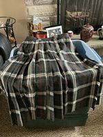 Full view of the pleated gray kilt with white and red plaid pattern spread out on container.
