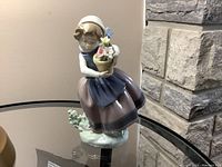 Front view of Lladro porcelain figurine depicting a young girl holding a flower pot with flowers, in pastel colors.