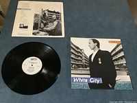 Top view of the Pete Townshend White City vinyl record alongside its album cover and inner sleeve on a blue surface.