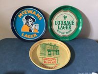Front view displaying three British beer trays featuring McEwan's Lager, Courage Lager Export Beer, and Newton and Ridley Best Bitter logos.