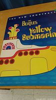 Close-up of the front side of the Beatles Yellow Submarine poster showing the yellow submarine with red, white and blue accents and text.