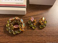 Brooch and clip-on earrings set displayed on wooden surface with Eaton's box in background