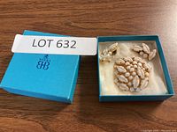 Photo of blue BIRKS box with brooch and earrings inside on white padding.