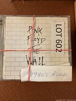 Pink Floyd The Wall CD cover with white brick wall design, bundle tagged as Lot 602 with 1980's rock note.