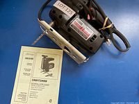 Photo showing Craftsman scroller saw and instruction manual with model and safety information visible.