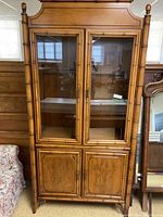 Full view of wooden display cabinet with glass upper doors and etched lower wooden doors.