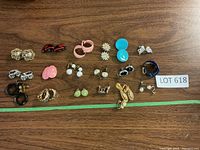 Overview of all earrings laid out on wooden surface showing variety in color, style, and size.