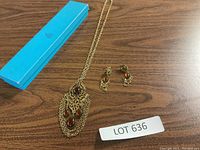 Photo showing gold tone necklace with brown stones, matching earrings, and blue Birks box