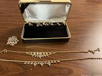 Full view of two necklaces, a brooch, and six pairs of earrings in a case.