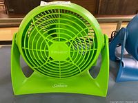 Front view of green Sunbeam Blizzard portable fan showing the 'Blizzard' name on the grille and 'Sunbeam' on the base.
