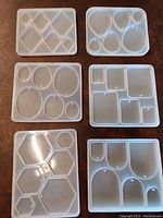 Photo showing 6 white translucent silicone jewelry making molds with various geometric shapes and sizes including diamonds, teardrops, ovals, circles, rectangles, squares, and hexagons.